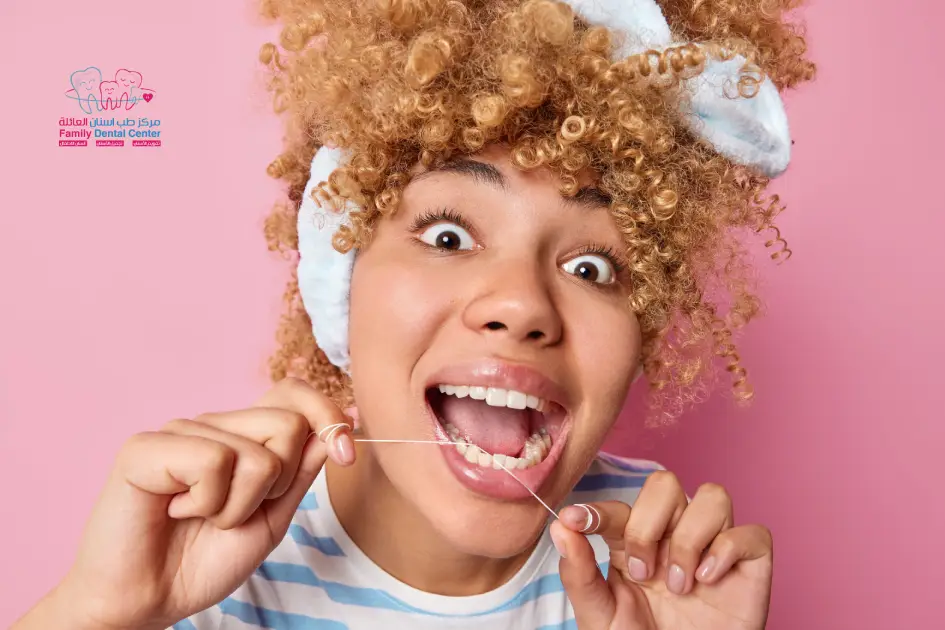 صورة لفتاة تستخدم خيط الاسنان لتنظيف اسنانها